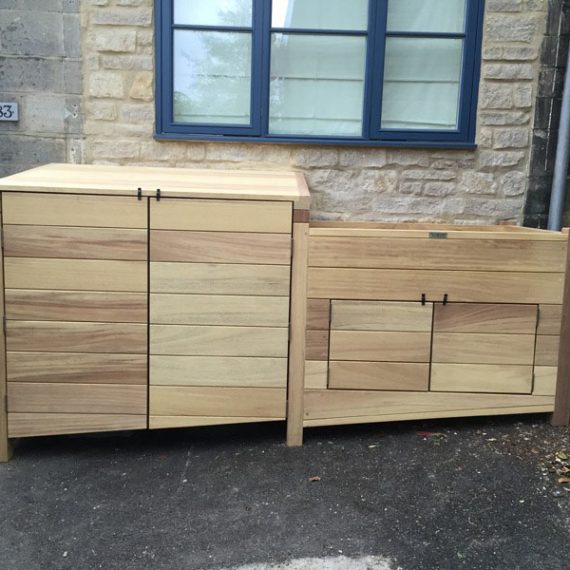 Bespoke luxury hardwood double wheelie bin store and integrated planter box, made with a sloped base to sit flush on an uneven street pavement under a window.