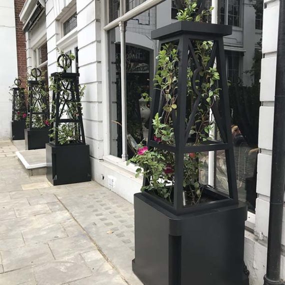 Bespoke black Accoya wooden planters with integrated Art Deco obelisks outside a property on King's Road, Chelsea, London.