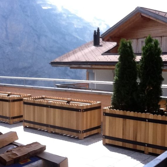 Bespoke scalloped hardwood trough planter with removable panels in Switzerland.