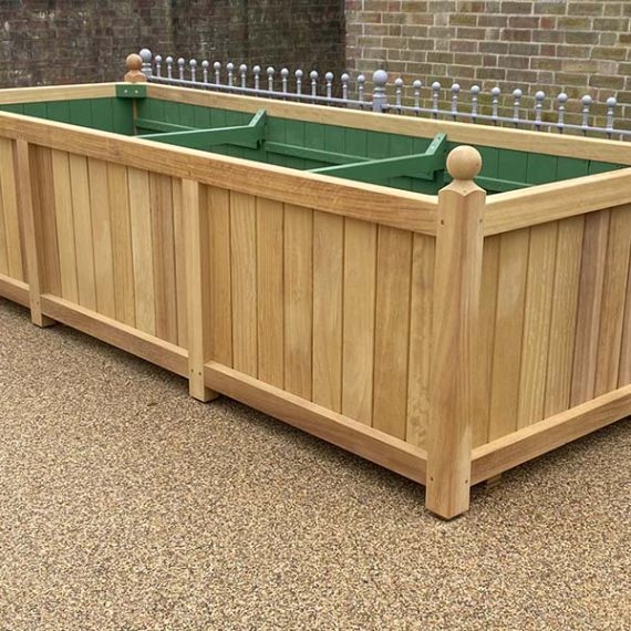 Extra large bespoke hardwood trough planter with natural timber finish, traditional panelled sides and decorative ball finials.
