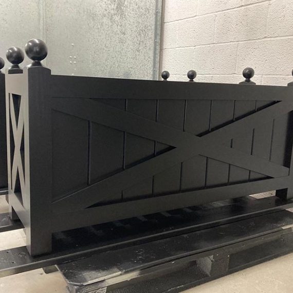 Bespoke black painted Regency wooden trough planters with decorative cross-braced panels and traditional ball finials.