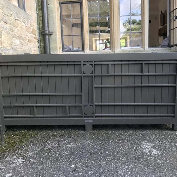 Oversized bespoke grey Accoya wooden trough planter with Rennie Mackintosh-inspired geometric detailing, positioned outside a traditional stone building..