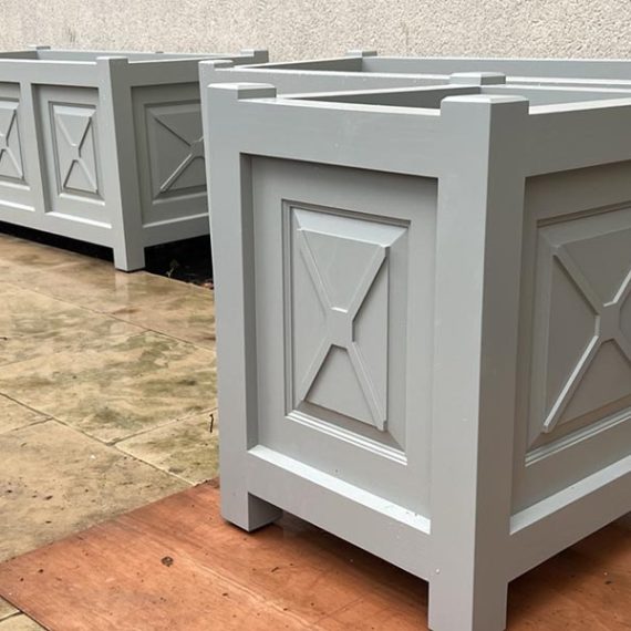 Bespoke made-to-order timber cube and trough planters, featuring traditional raised fielded panels with cross details and a flawless light grey painted finish.