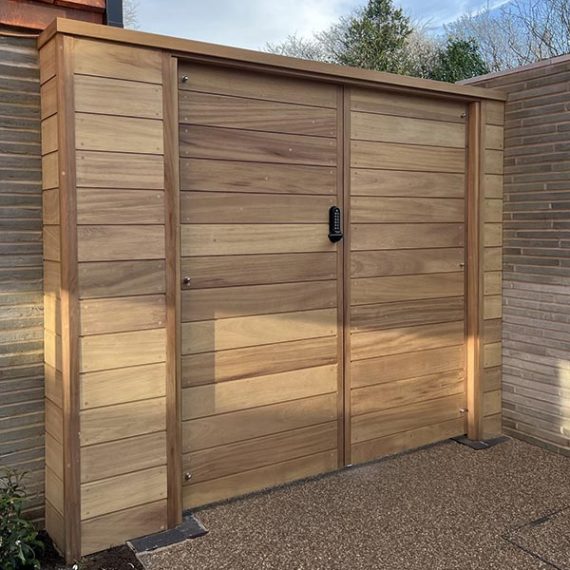 Modern horizontal timber garden gate with a mechanical keypad lock, built into a recessed brick entryway