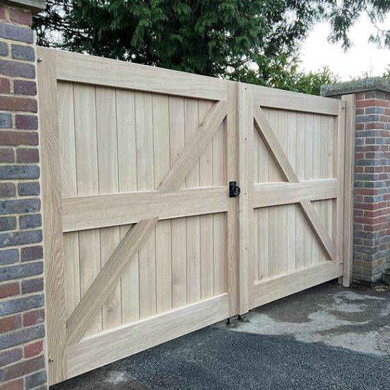 Luxury Arts and Crafts timber entrance gates, handcrafted by Oxford Planters from natural hardwood and recessed between traditional brick pillars.