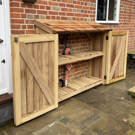 Luxury outdoor cupboard storage unit with a cedar shingle roof. Made bespoke in hardwood to hide pipes in the back.