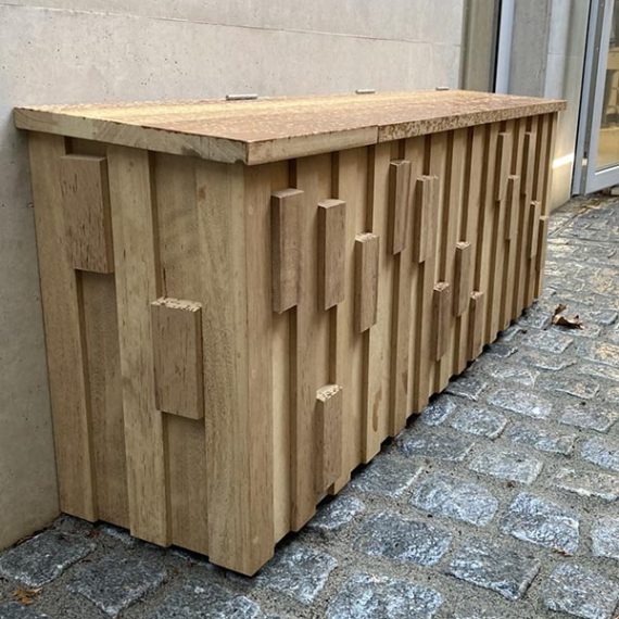 Art Deco style bespoke solid oak outdoor storage cupboard featuring a textured geometric block pattern on vertical timber slats fixed to a wall.