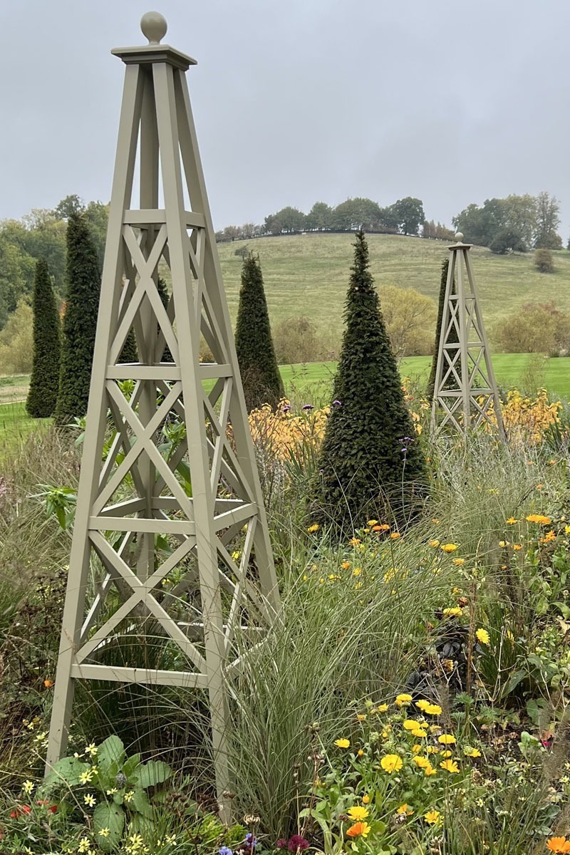 Tall handmade obelisk with cross detail painted in a green hue.
