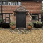 Pair of large black Exeter Georgian-style wooden trough planters outside a traditional brick and timber house.