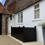 Large bespoke black painted Accoya wooden trough planter with deep traditional panelled sides outside a country house.