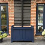Blue painted Accoya wooden trough planter with traditional detailing outside a brick house.