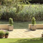 Hertford oak wooden garden planters on the terrace of a private Cotswold country estate overlooking a lake.